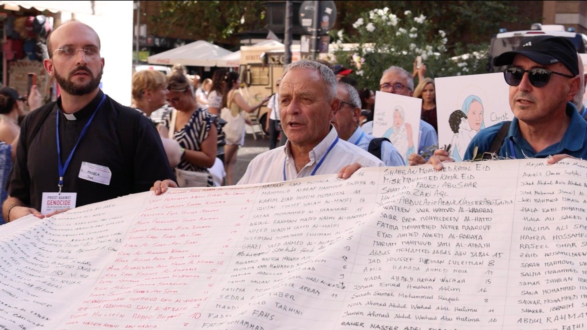 Священники, выступающие против геноцида, держат плащаницу с именами детей, убитых в Газе
